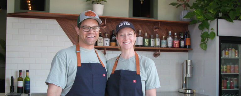 Two business owners smiling in front of their business
